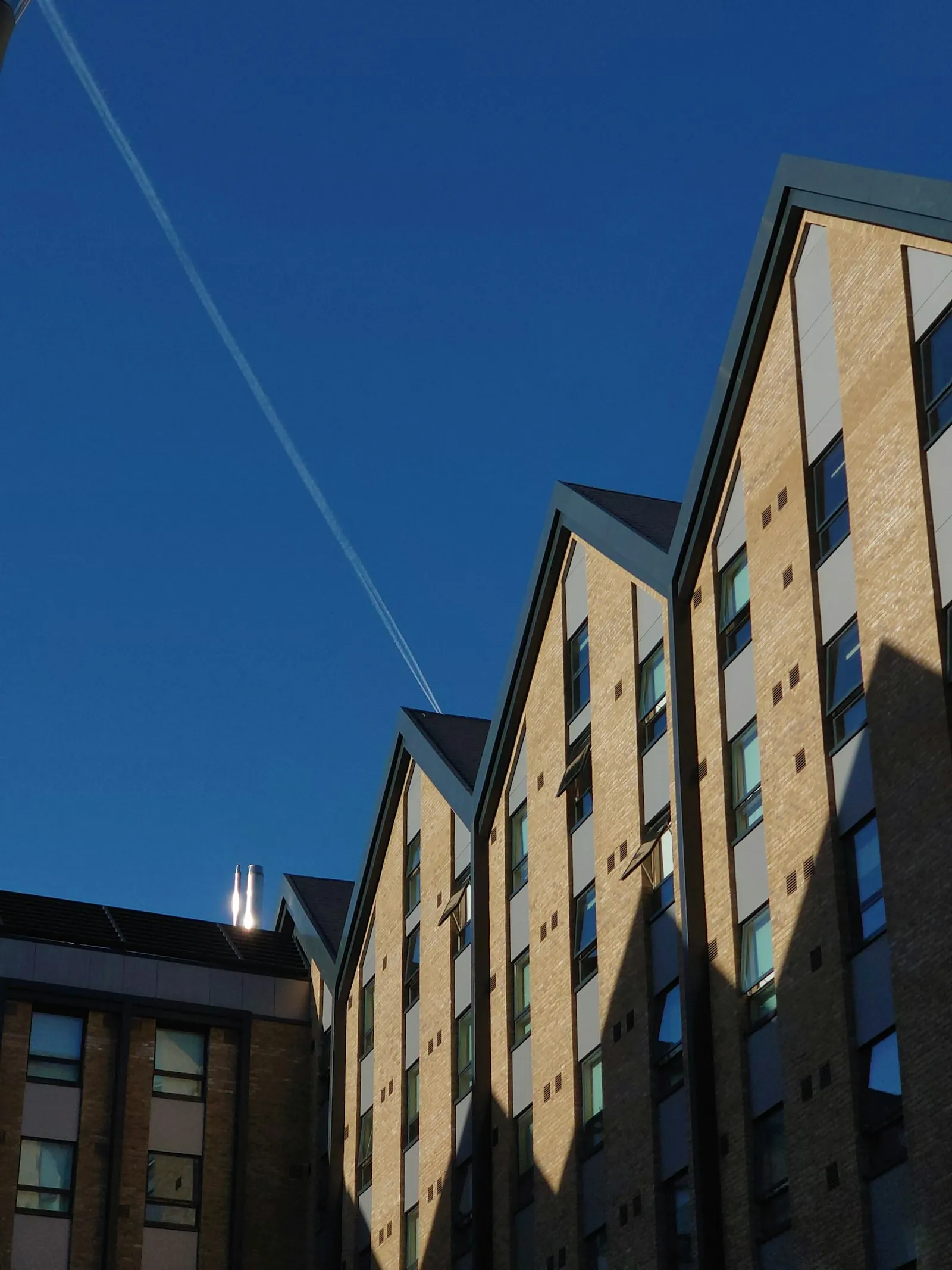 Brick-built housing with gabled roofs against a clear blue sky