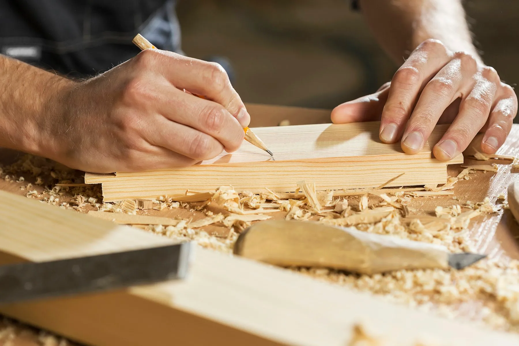 A carpenter marking out a length of timber by hand