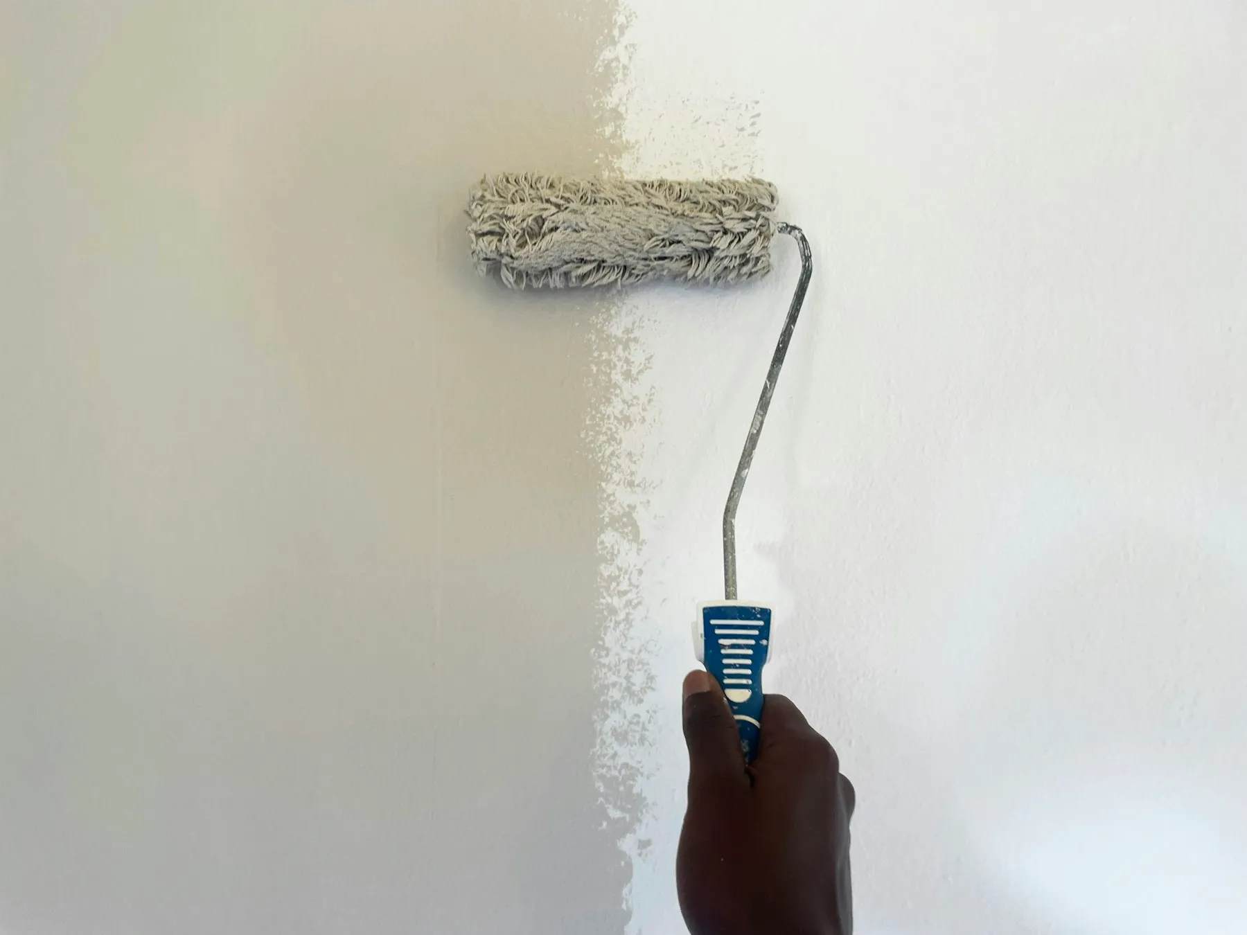 A roller being used to apply fresh paint to a wall